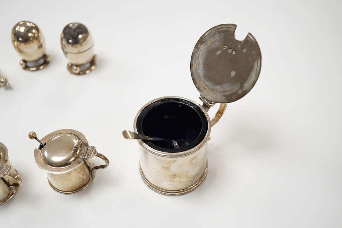 A George V silver mustard pot, London, 1931, with blue glass liner and associated silver shovel, together with a George V silver pepperette, a pair of small silver mustard pots and spoons, a pair of small silver pepperet